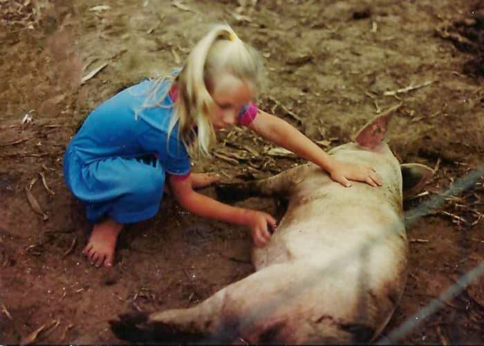 Hicks, Hoodlums, & Highrises author, Nicole Braun, as a child rubs a pigs belly