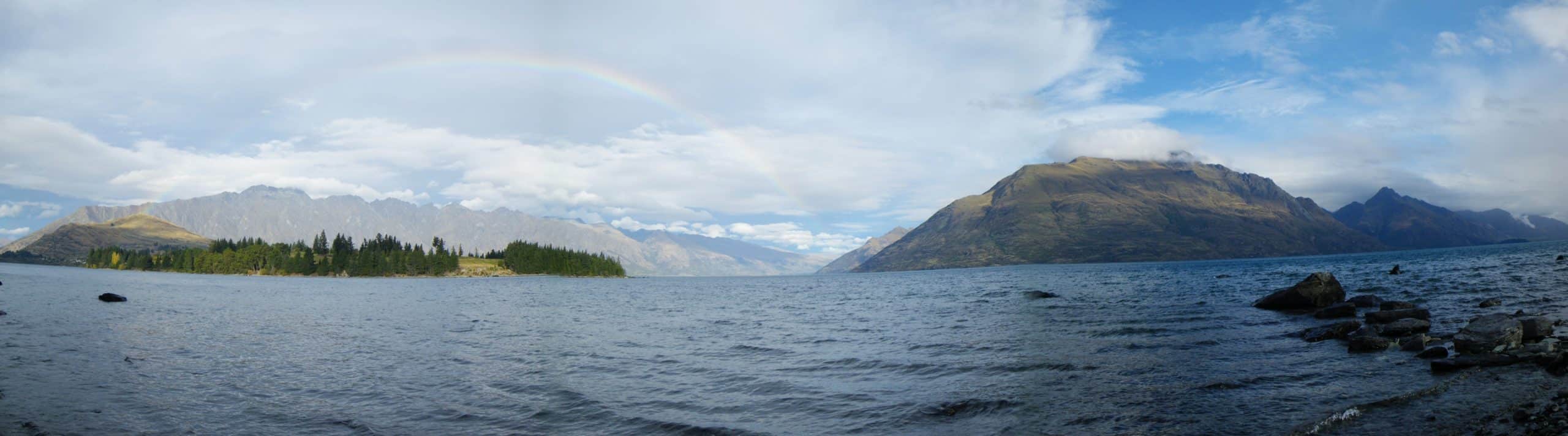 A rainbow shines over the mountains along the coast of lake Wakatipu in Queenstown, New Zealand