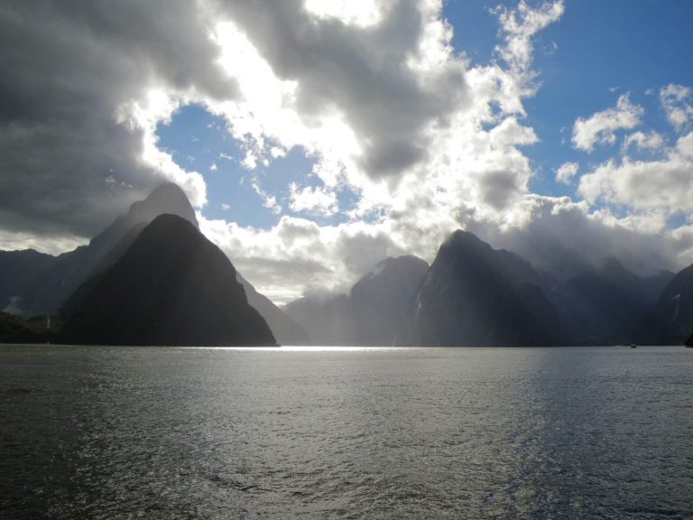 The sun breaks through the clouds in Milford Sound, New Zealand